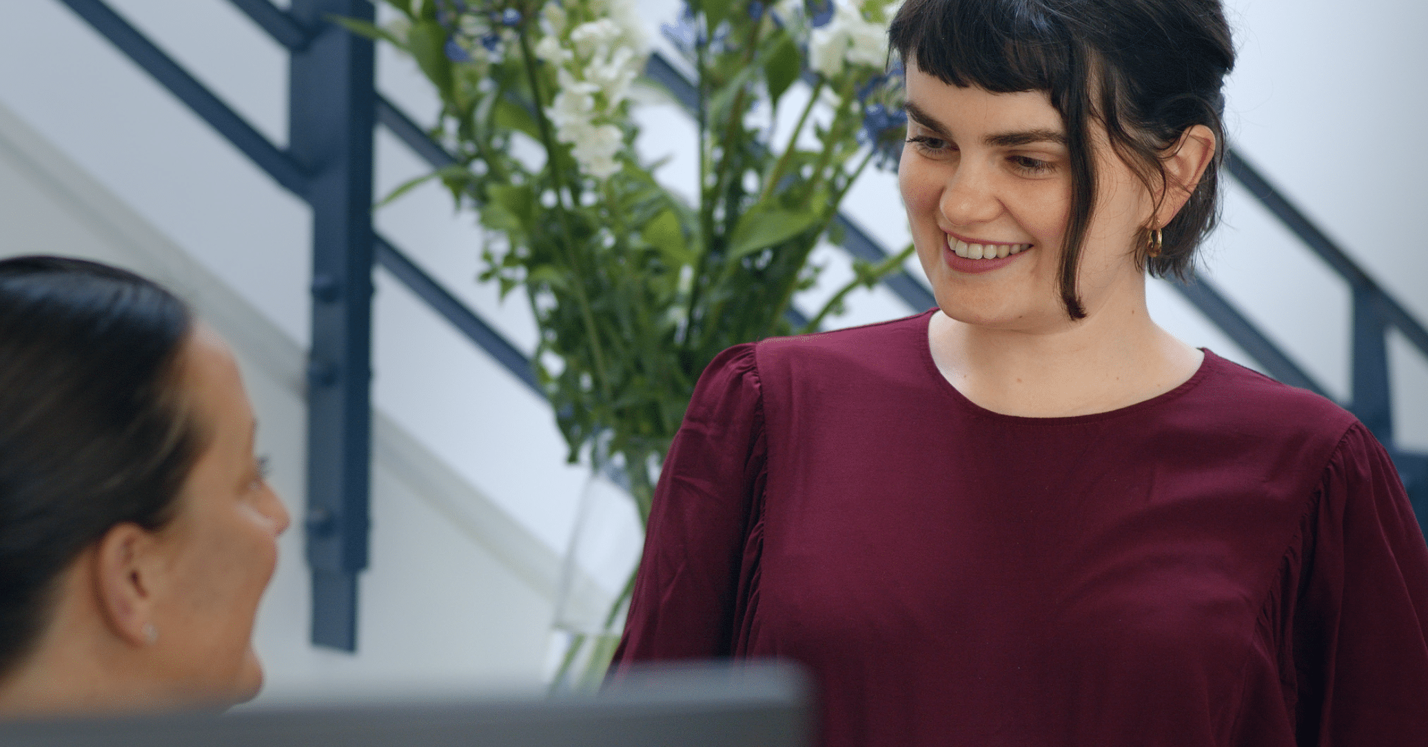 Two women smiling and chatting indoors.