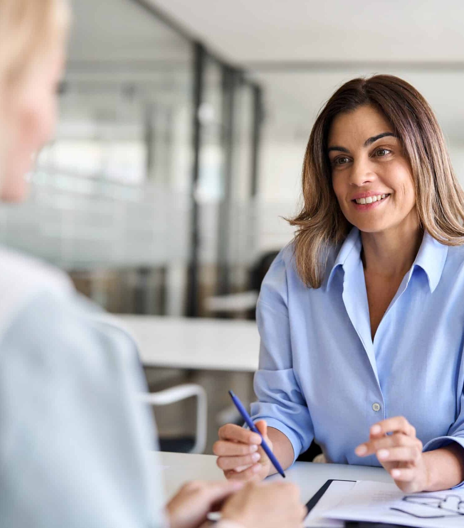 Deux femmes discutent dans un bureau moderne.