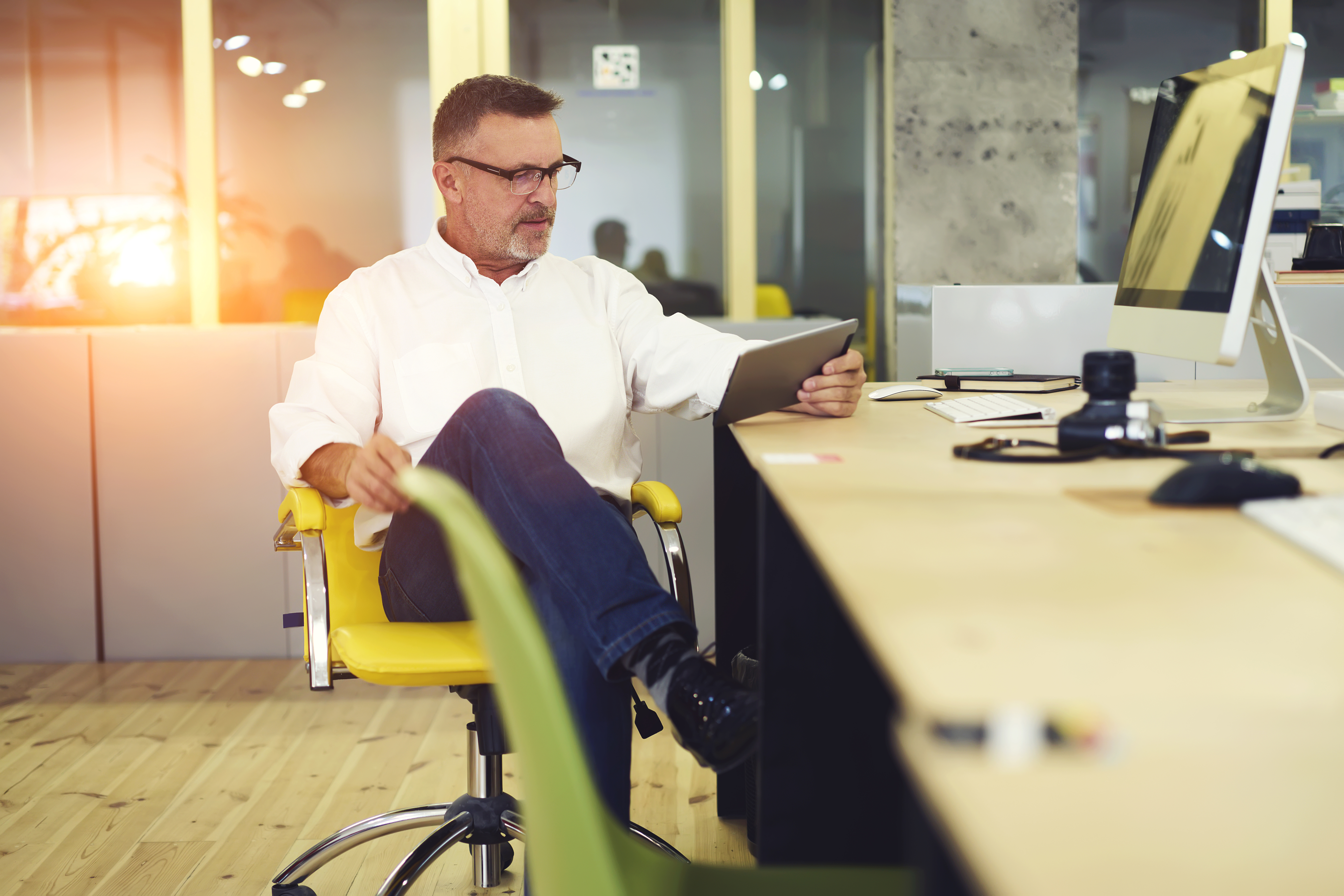 Homme consultant une tablette dans un bureau moderne.